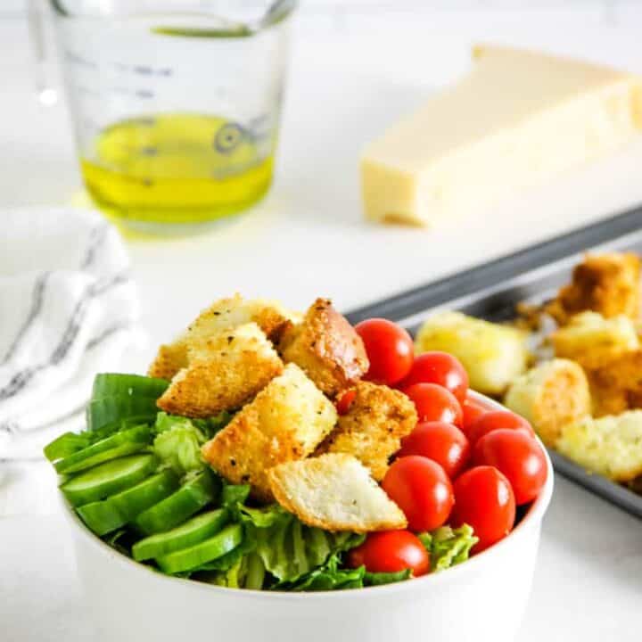 croutons topped on salad in white bowl.