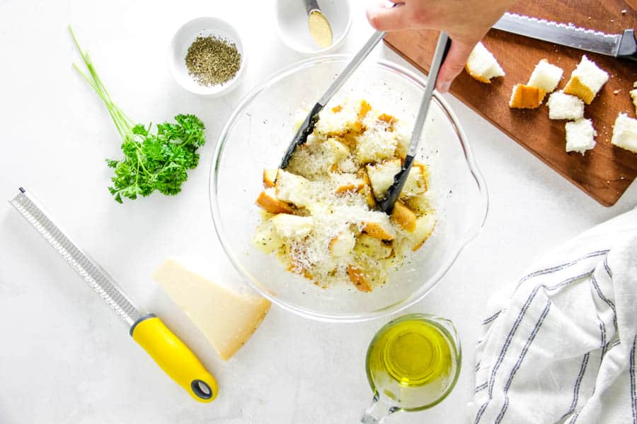 tossing cubed bread in glass bowl.