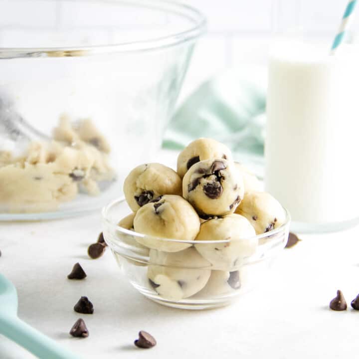 cookie dough bites in bowl with glass of milk.