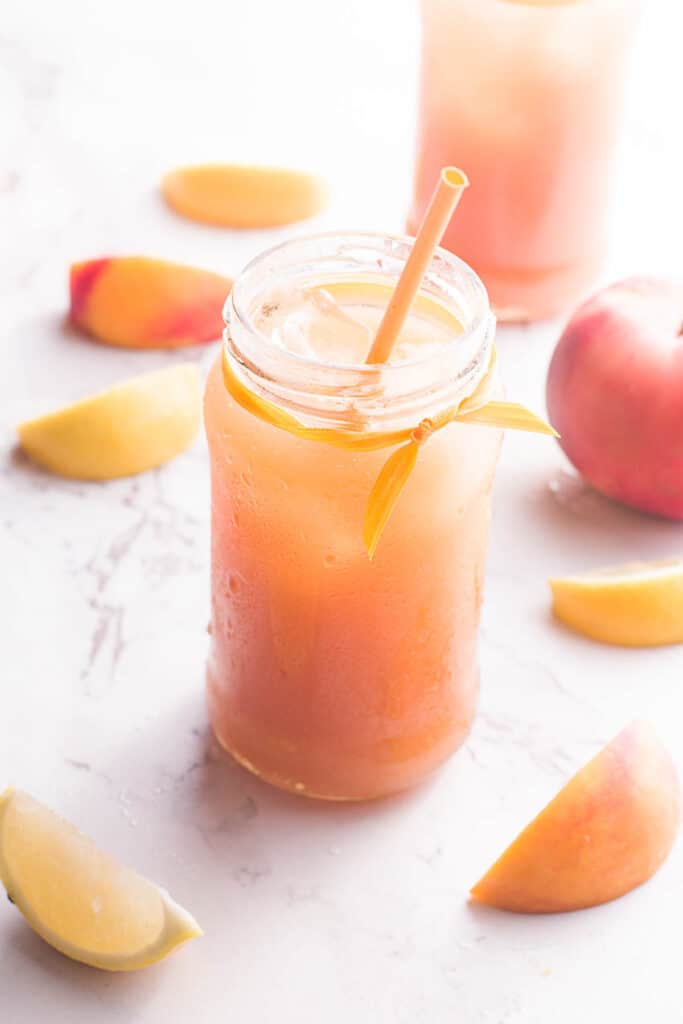 Peach Black Tea Lemonade in glass jar with straw.