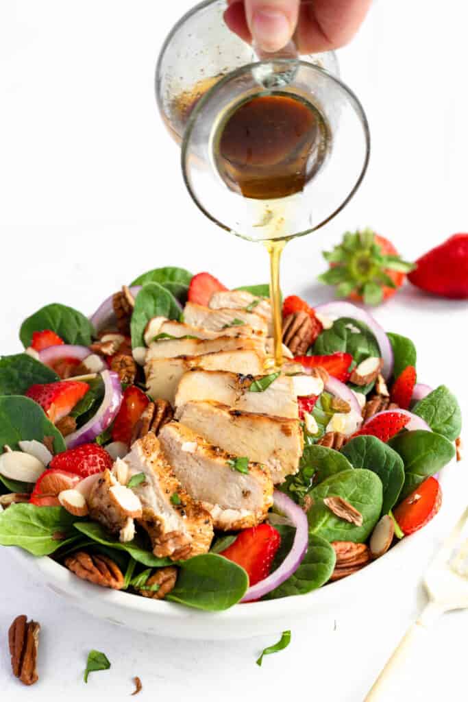 Drizzling dressing on Strawberry Chicken Spinach Salad.