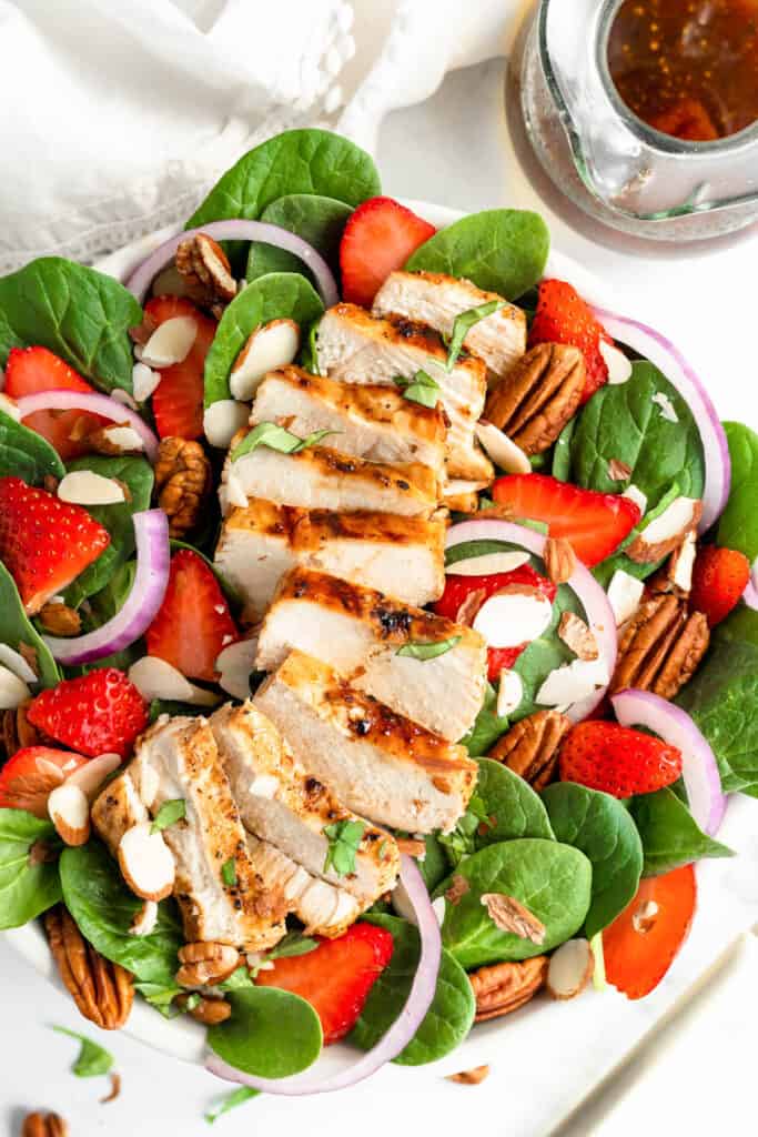 Strawberry Chicken Spinach Salad in bowl topped with pecans.