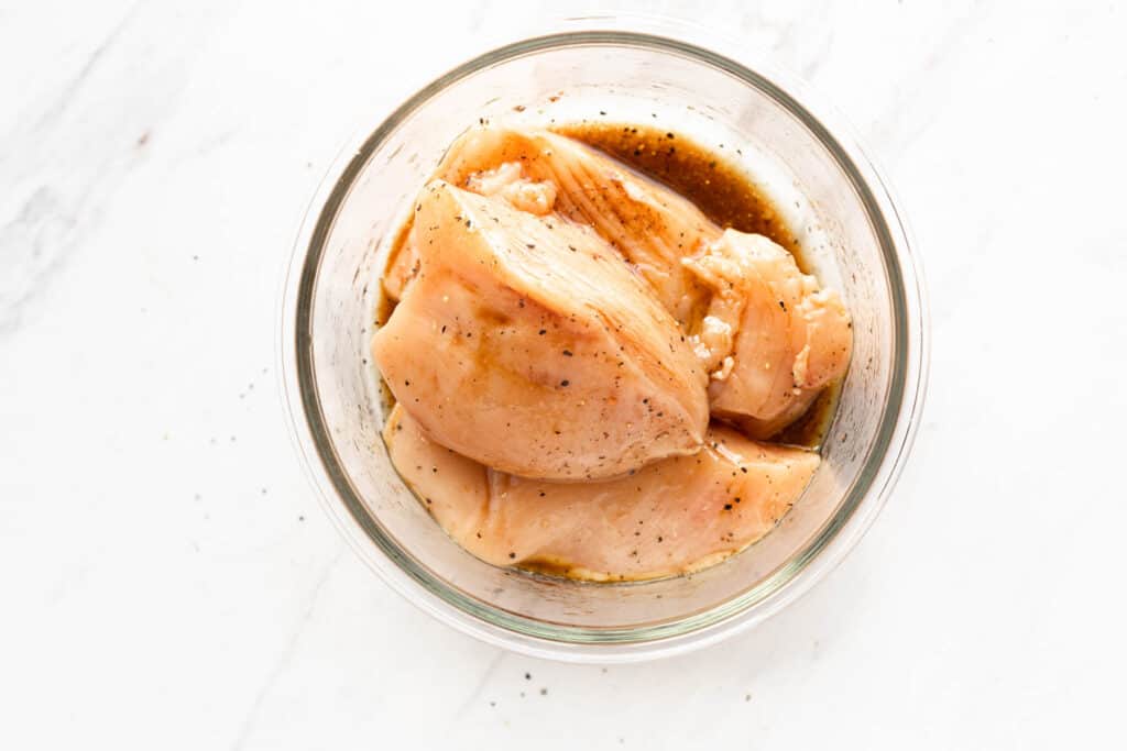 chicken marinating in glass bowl.