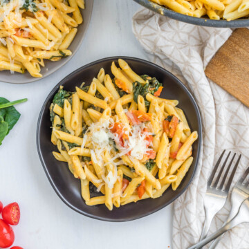 Creamy Tomato Spinach Pasta topped with cheese.