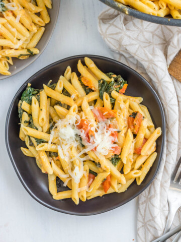 Creamy Tomato Spinach Pasta topped with cheese.