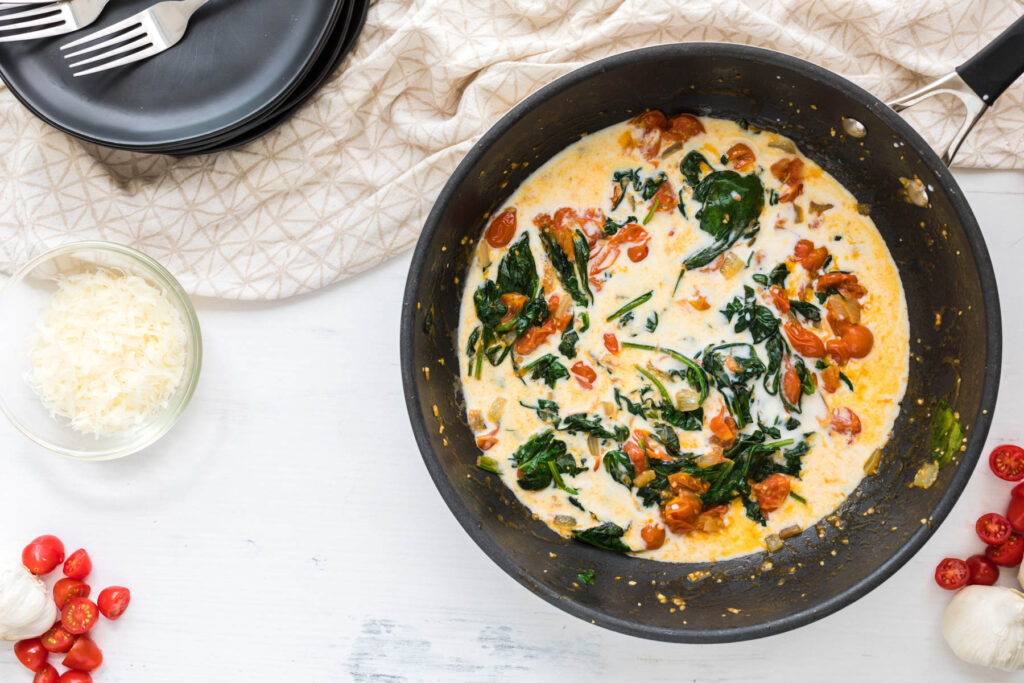 tomatoes and spinach cooked in saute pan with cream.