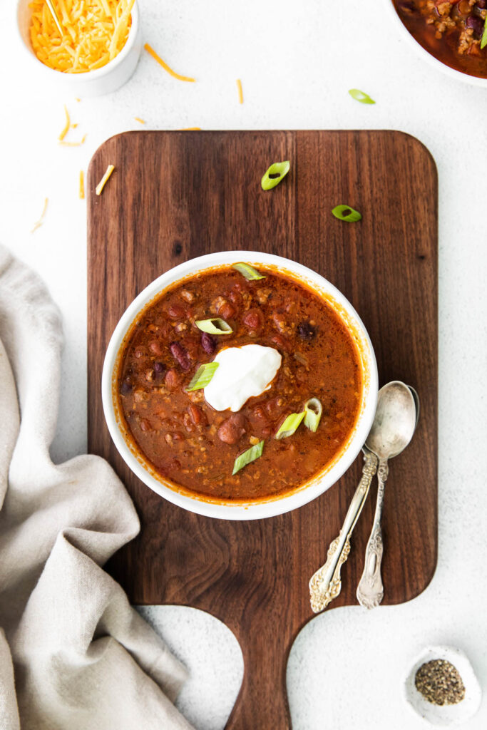 Slow Cooker Chili overhead view with bowl on brown background.