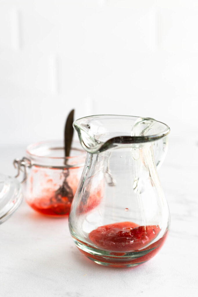 adding strawberry jam to glass pitcher.