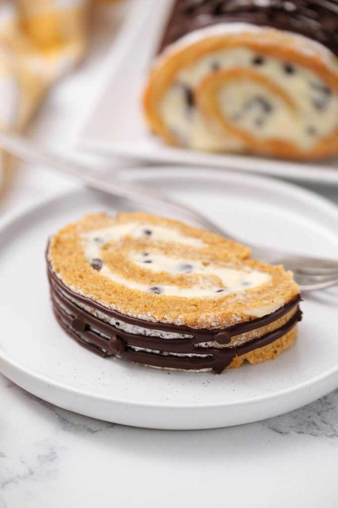 slice of Chocolate Chip Pumpkin Roll on white plate.