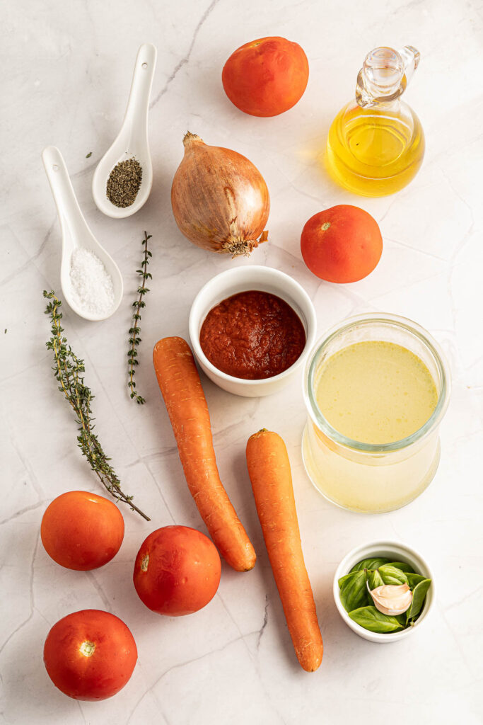 This Homemade Tomato Soup cooks up in just about 30 minutes! Creamy, rich, and filled with fresh tomatoes and basil! ingredients of homemade tomato soup on white background.