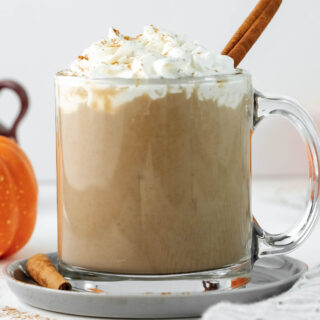latte in glass cup topped with cream.