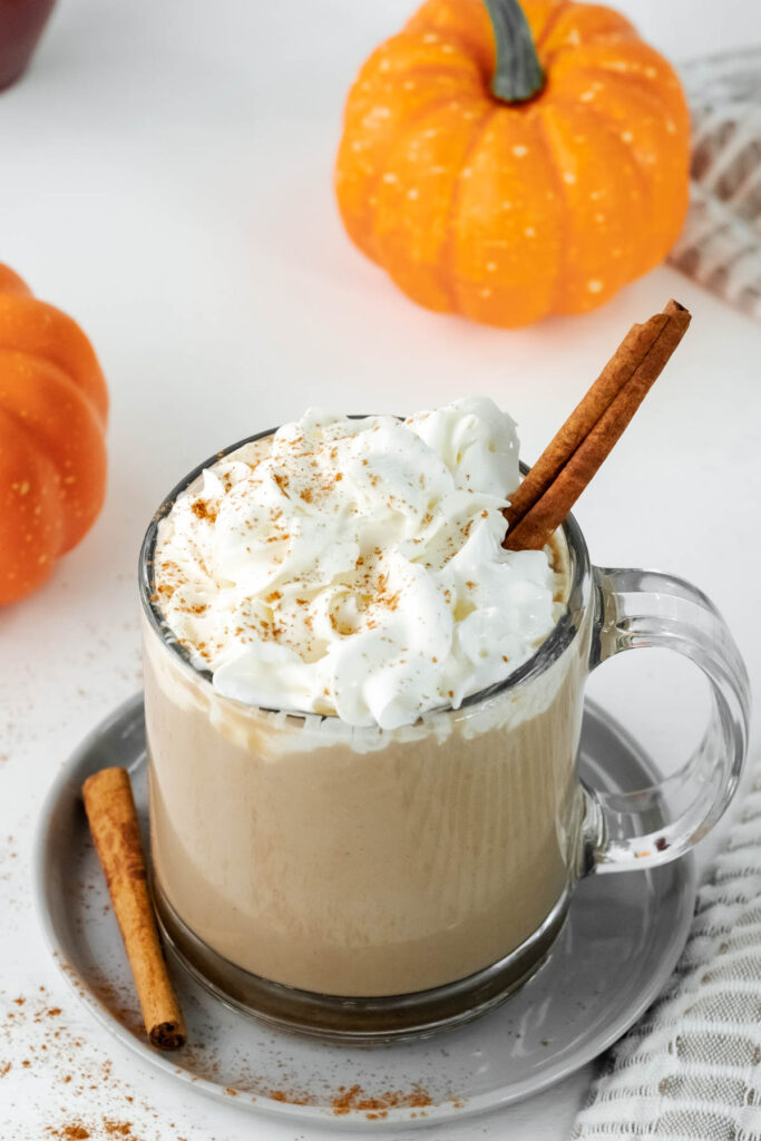 latte in glass cup with cream topped with cinnamon.