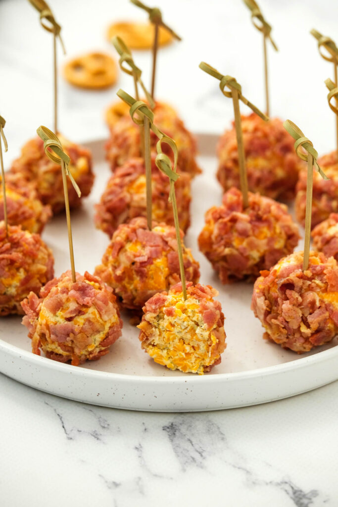 These Mini Bacon Ranch Cheeseballs are perfect for snacking! Made with cream cheese, ranch dressing and bacon bits! Mini Bacon Ranch Cheeseballs cut open on white plate.