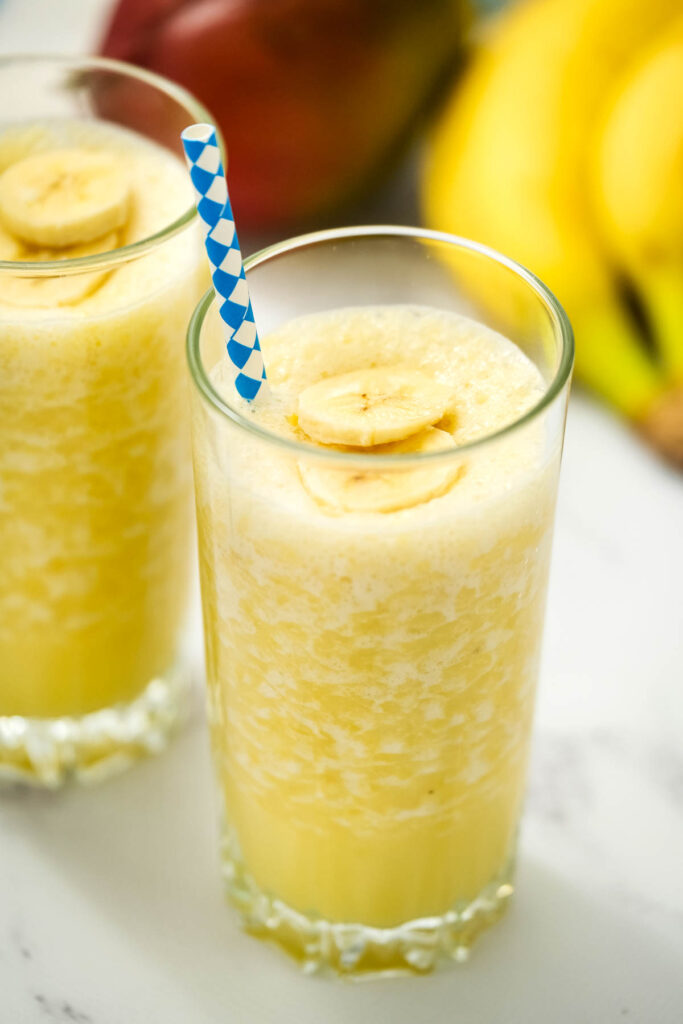 Mango Banana Smoothie in glass with straw.