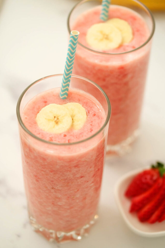 Strawberry Banana Smoothie in glasses topped with fresh bananas.