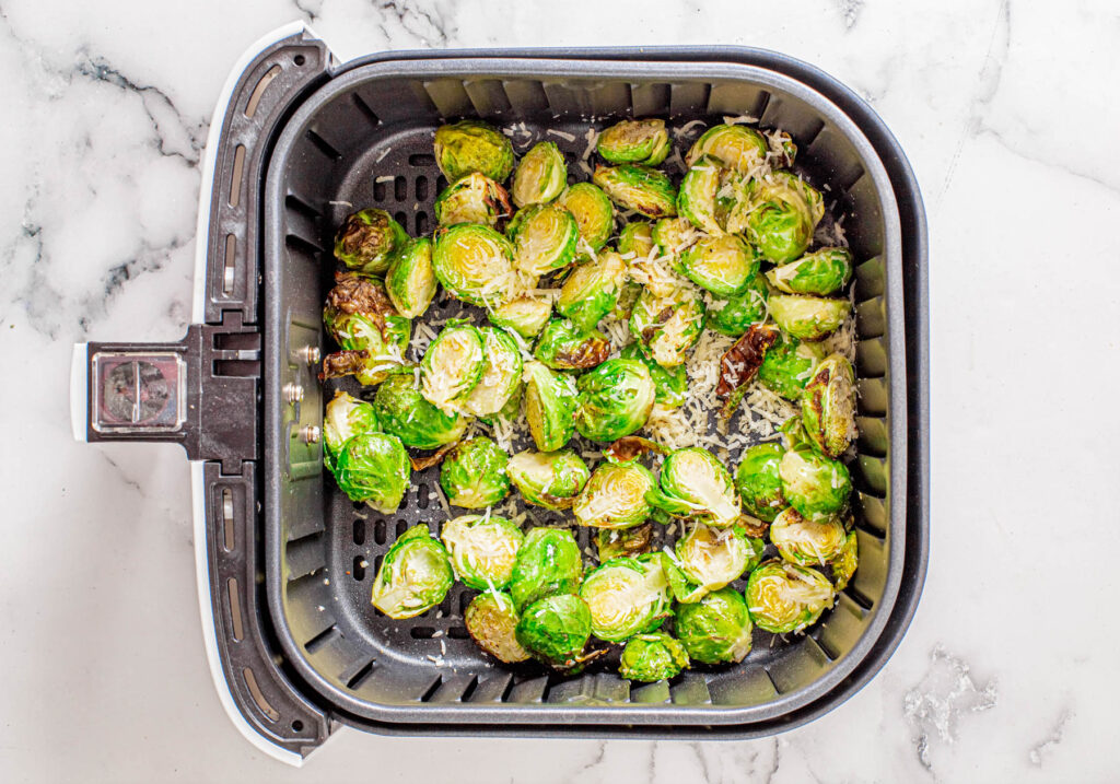 half cooked sprouts in air fryer with Parmesan.