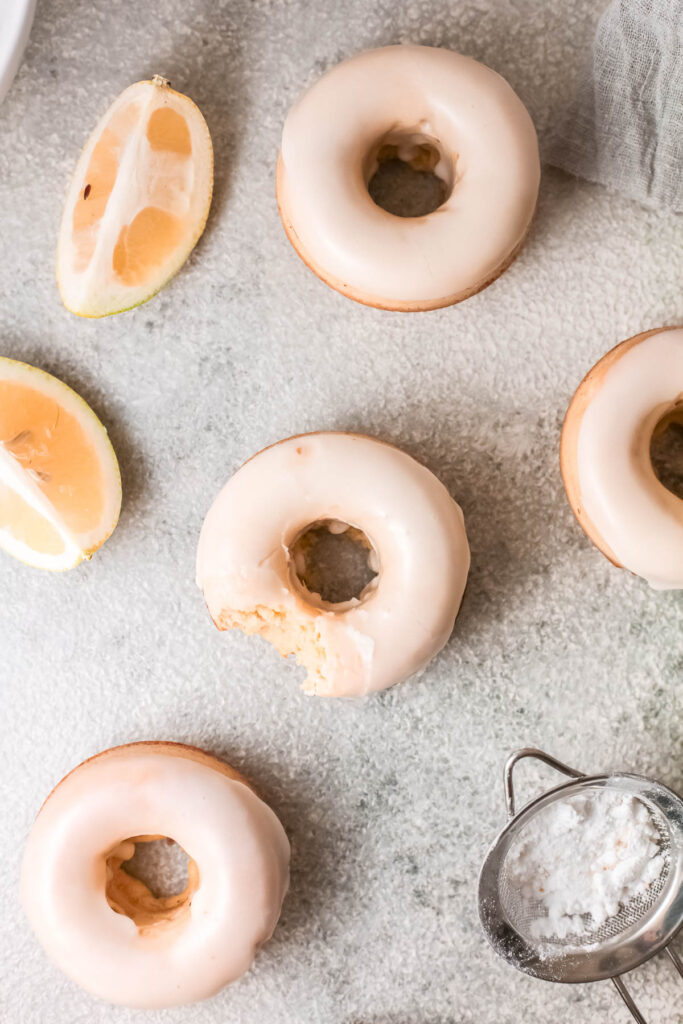 Baked Lemon Donuts on gray back ground with lemon wedges.