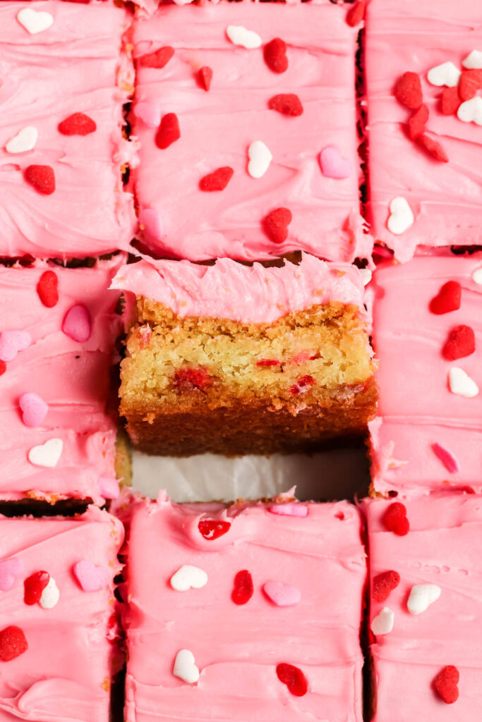 Strawberry Frosted Cookie Bars with square pulled up in center.