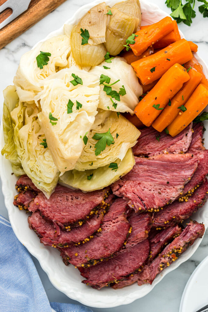 instant pot corned beef sliced on white plate with veggies.
