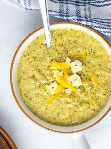 soup in bowl with silver spoon topped with crackers.