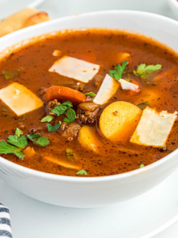 soup in bowl topped with cheese and parsley.