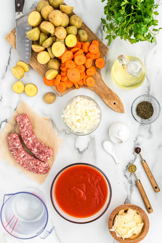 sausage vegetable soup ingredients laid out on white background.