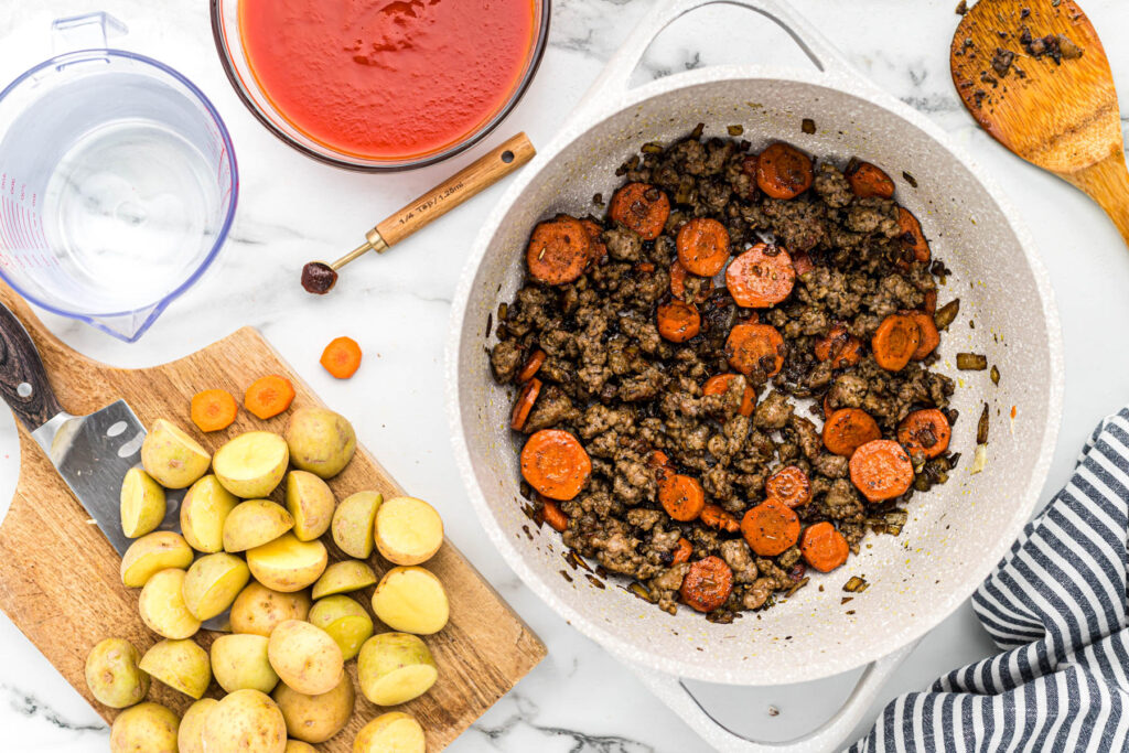 carrots and sausage cooked in pan.