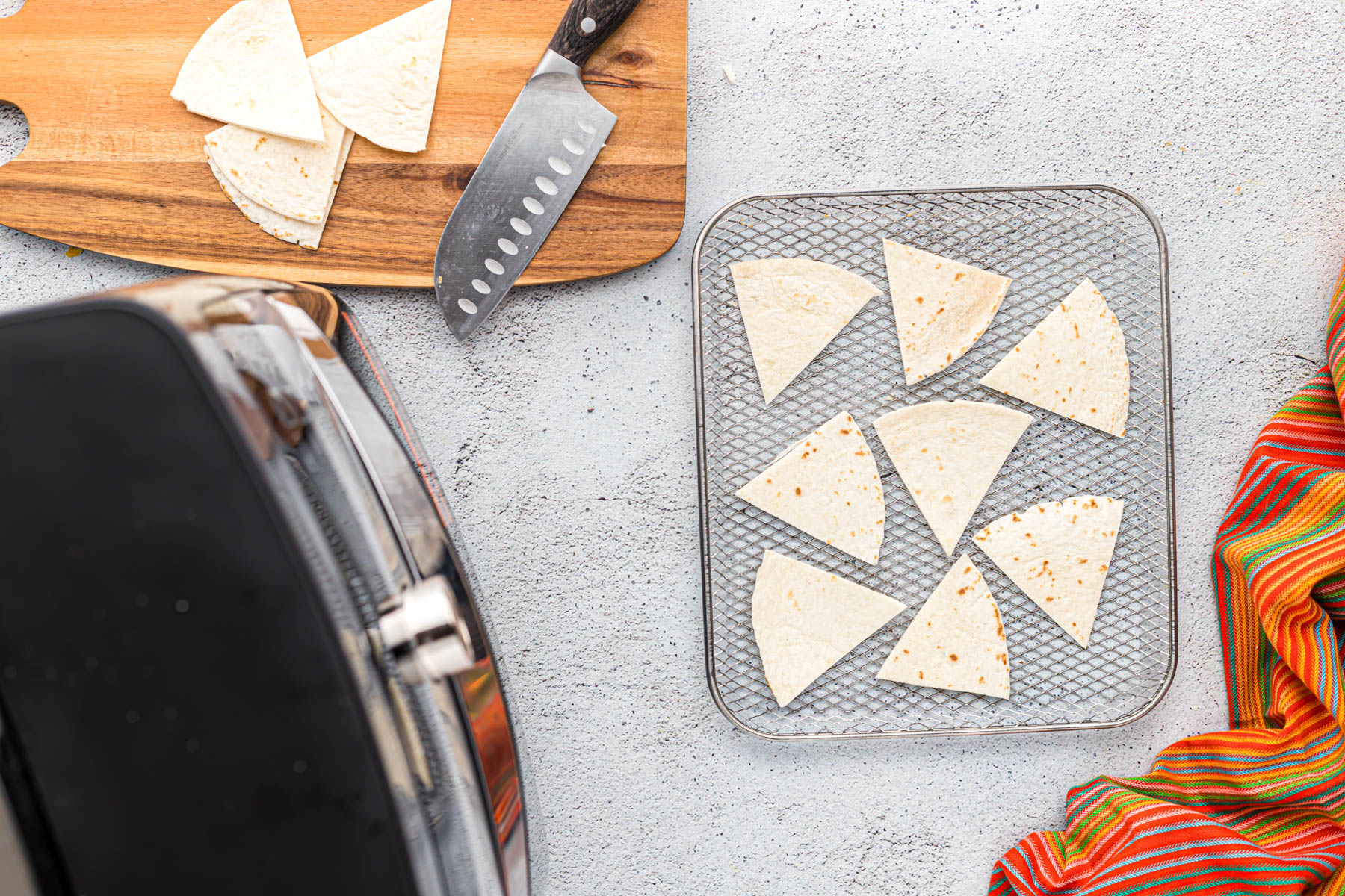 uncooked flour tortilla chips on air fryer tray.