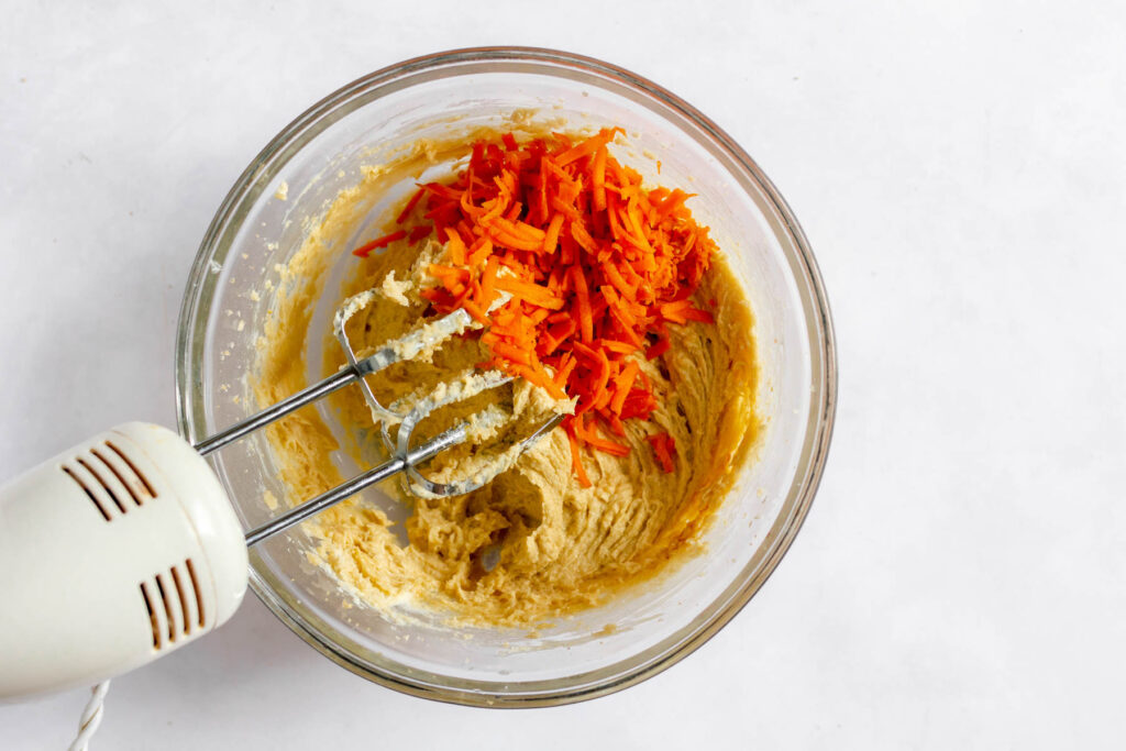 shredded carrots in glass bowl with cookie dough.