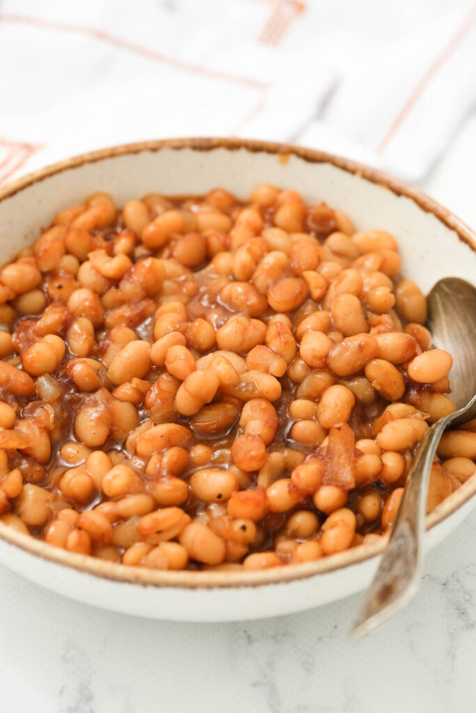 Homemade Baked Beans in white bowl with spoon.