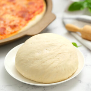 pizza dough on white plate.