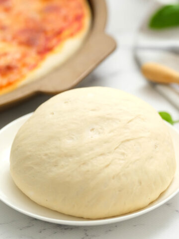 pizza dough on white plate.