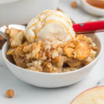 cobbler in bowl topped with ice cream.