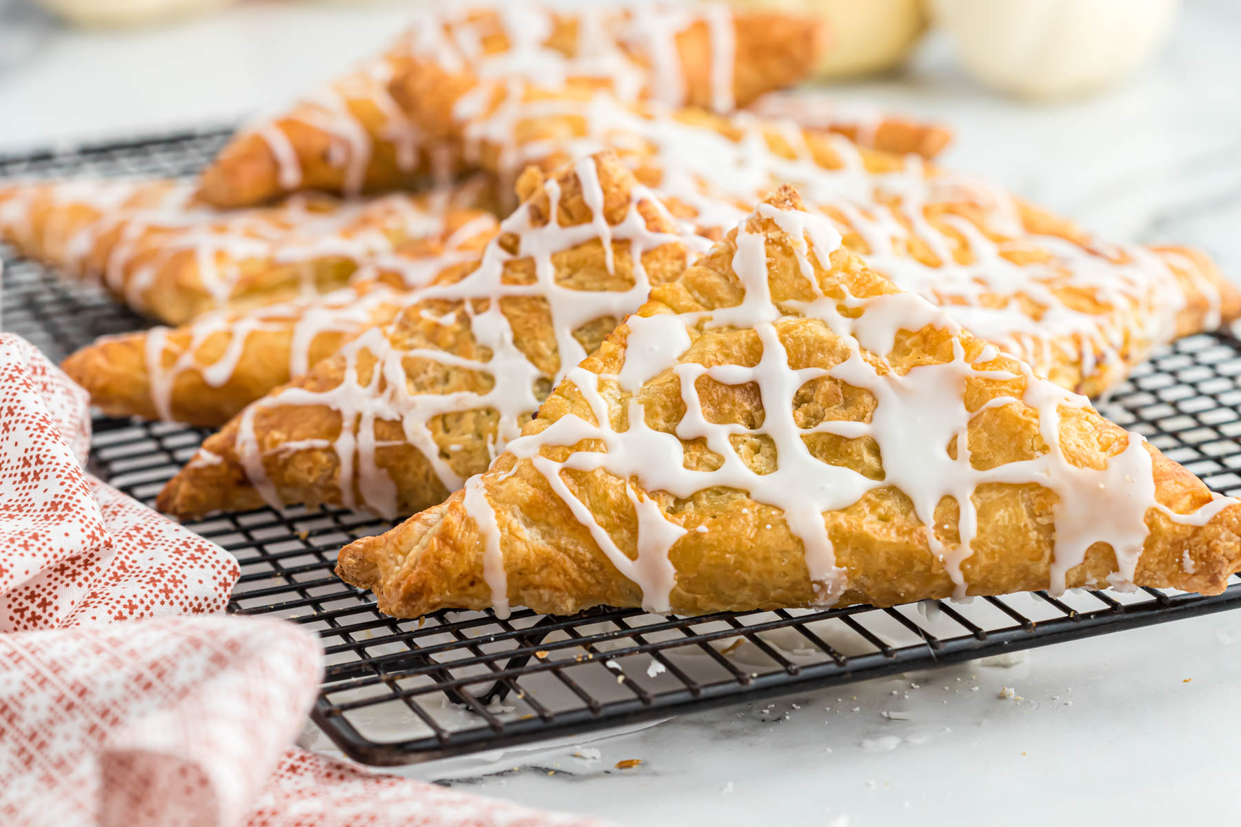 air fryer pumpkin turnovers on cooling rack drizzled with glaze.