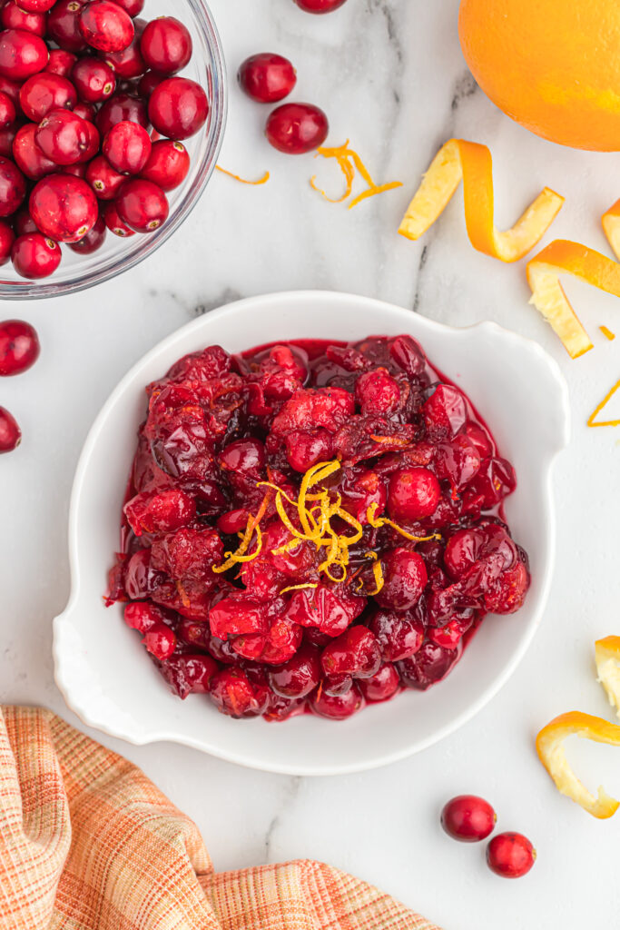 cranberry sauce with orange zest on top in white bowl.