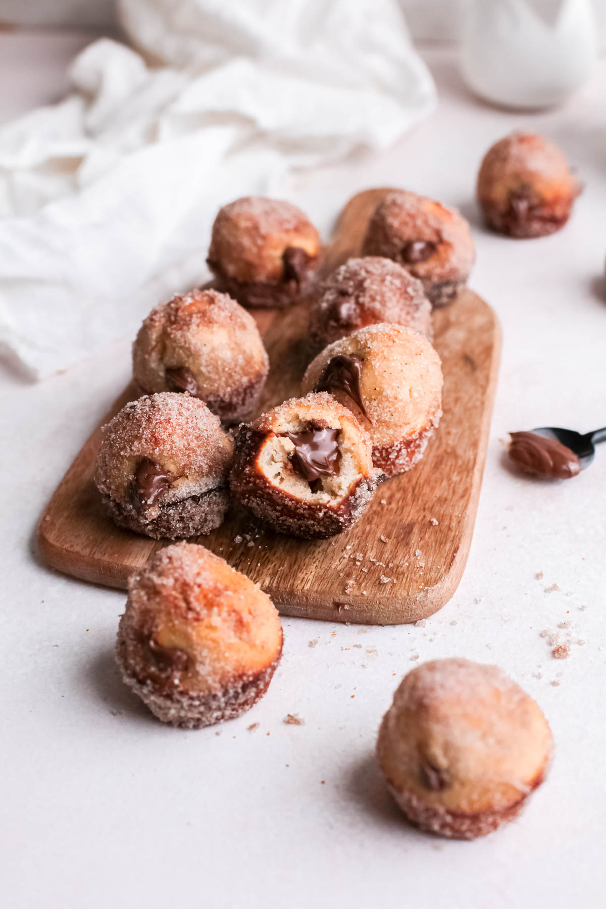Nutella Donut Holes stacked on wooden board.