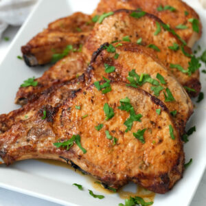 pork chops on white plate with parsley.