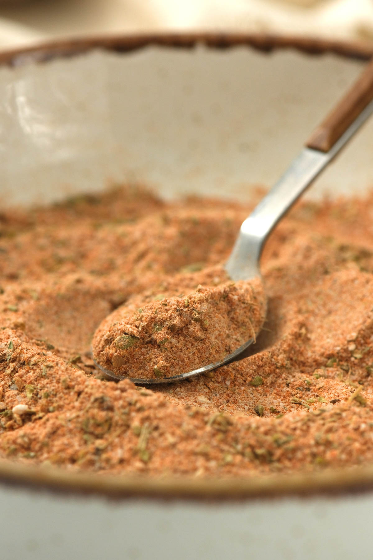 seasoning blend on spoon in white bowl.