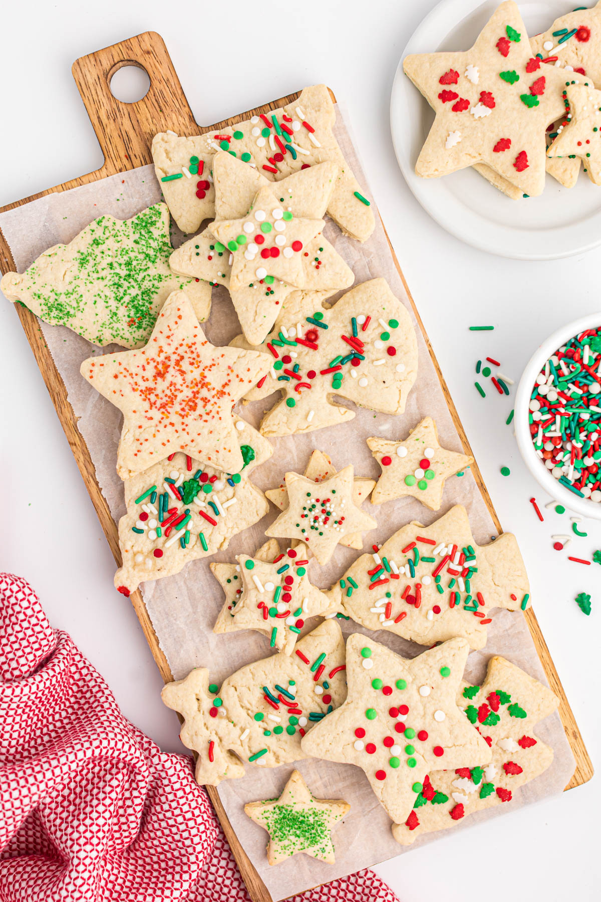 cut out cream cookies on parchment paper with sprinkles
