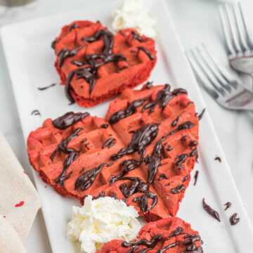 red velvet cake mix waffles in heart shaped on white plate.