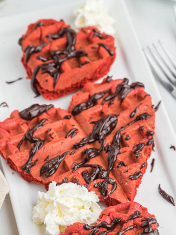 red velvet cake mix waffles in heart shaped on white plate.